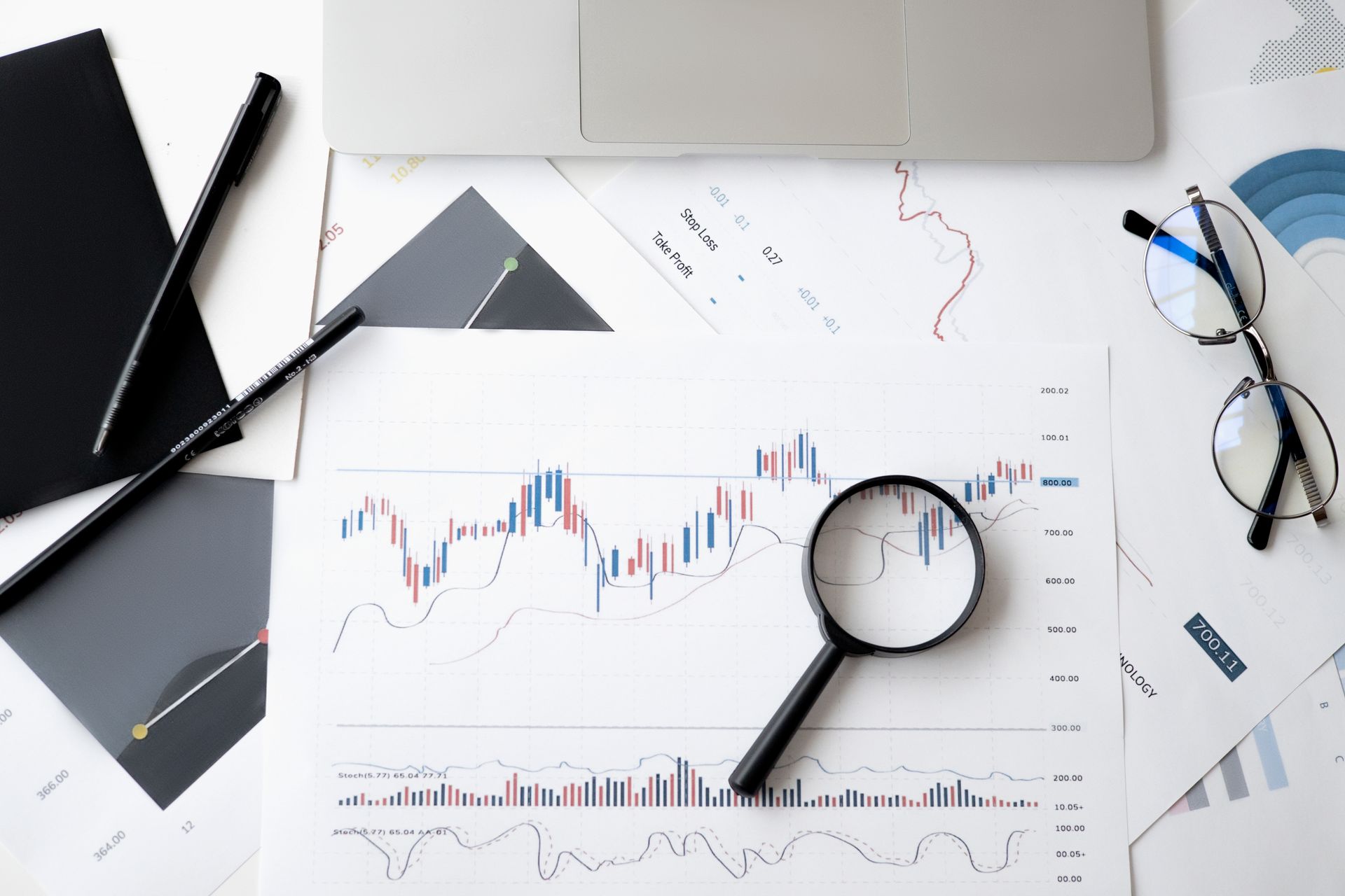 Trading desk with stop-loss notes, a printed chart, and a laptop — alerts you still have to act on